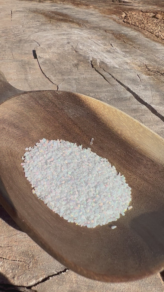 Video of Crushed Synthetic Fire & Snow Opal on wood bowl in full sunlight - Purple Door Alchemy